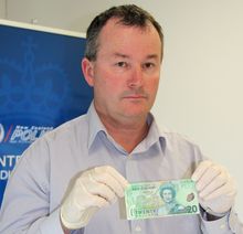 Acting Detective Sergeant Mike Freeman with a counterfeit $20 note.