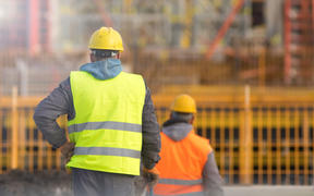 Two builders in yellow and orange at the construction site