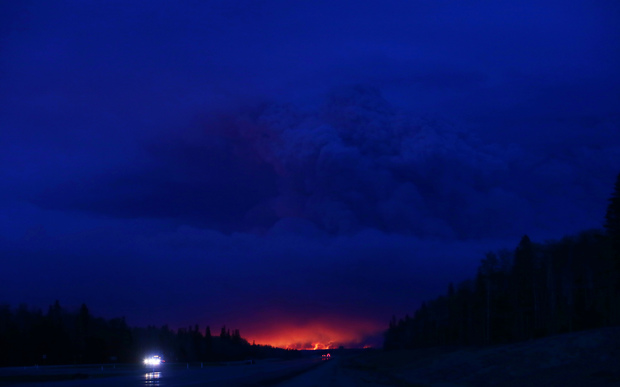 A plume of smoke hangs in the air as forest fires rage on in the distance in Fort McMurray.