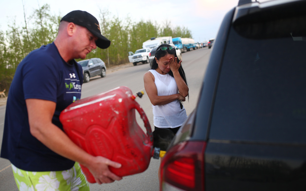 Marilou Wood fights back tears as husband Jim Wood fills up his car with gas after fleeing forest fires in Fort McMurray.
