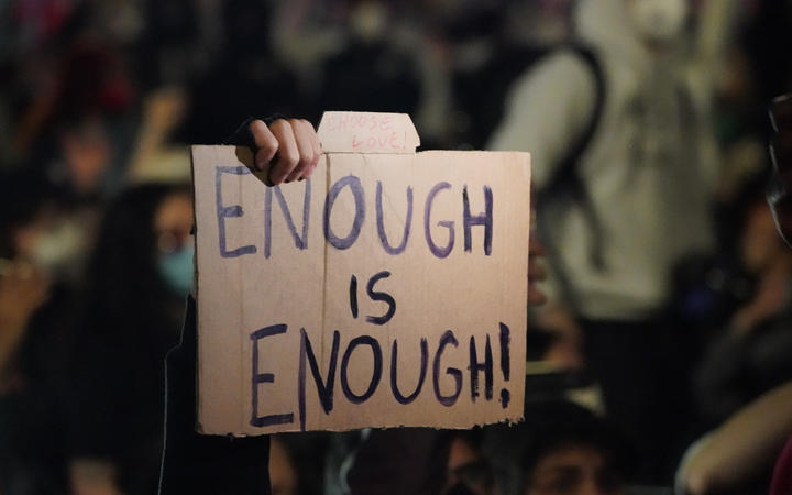 A person holds up a sign as protesters kneel on Canal St during a demonstration over the death of George Floyd in police custody in Minneapolis.