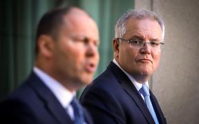 Australian Prime Minister Scott Morrison (R) reacts as he stands with the Australian Treasurer Josh Frydenberg