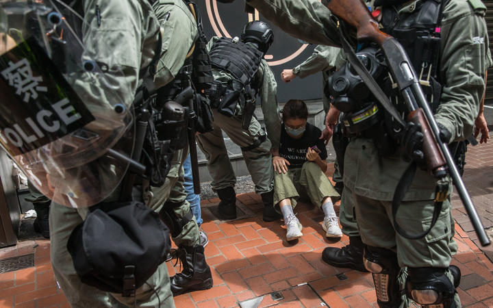 Riot police detain a woman as they clear protesters taking part in a rally against a new national security law in Hong Kong on July 1, 2020, on the 23rd anniversary of the city's handover from Britain to China. 