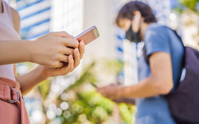 Contact tracing app COVID-19 pandemic coronavirus. People wearing masks using phones.