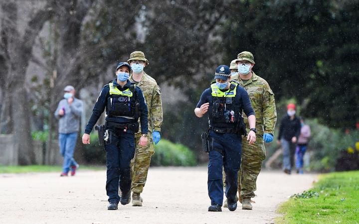 Police officers and soldiers patrol a popular running track in Melbourne on August 4, 2020 after the state announced new restrictions as the city battles fresh outbreaks of the COVID-19 coronavirus.