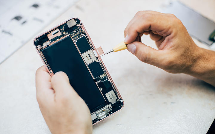 Technician repairs and inserts the sim memory card on the mobile phone in electronic smartphone technology service. Cellphone technology device maintenance engineer