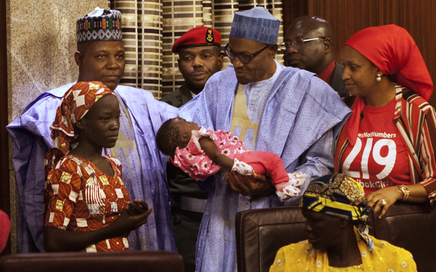 Nigerian President Mohammadu Buhari holds the daughter of Amina Ali Nkeki.