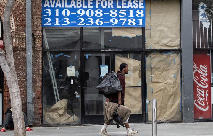 A homeless person walks by a closed business with a sign reading "For Lease" in Santa Monica, California, amid the coronavirus pandemic.