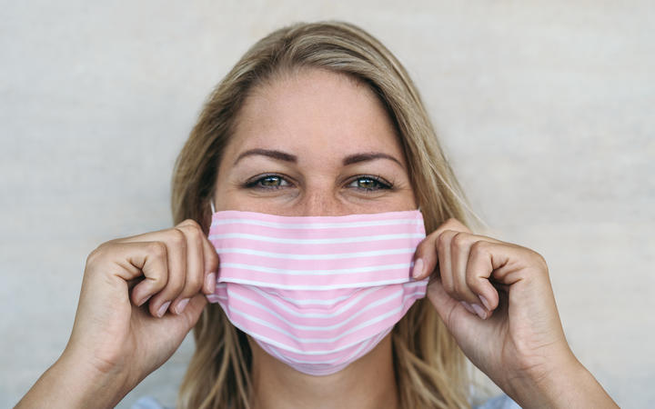 Young woman wearing pink face mask portrait - Blonde female using protective facemask for preventing spread of corona virus 