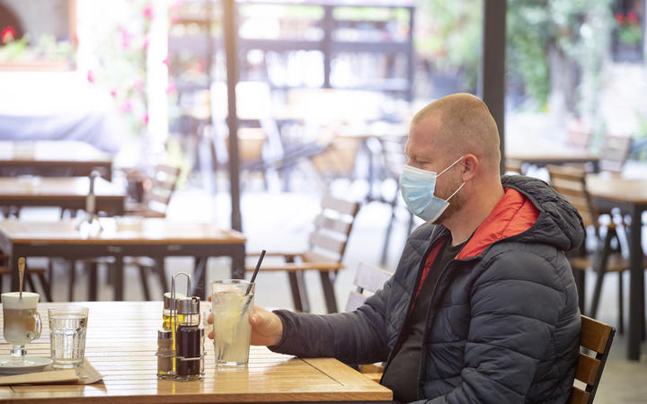 Man in restaurant wearing face mask to protect against Covid-19.