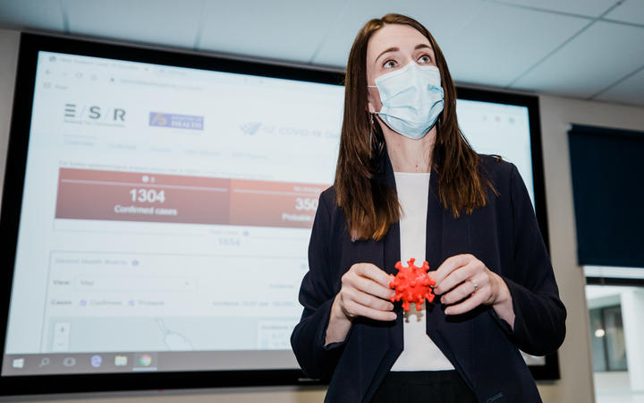 Prime Minister Jacinda Ardern wears a mask and holds a 3D model of the coronavirus during a visit to ESR in Porirua on 20 August 2020.