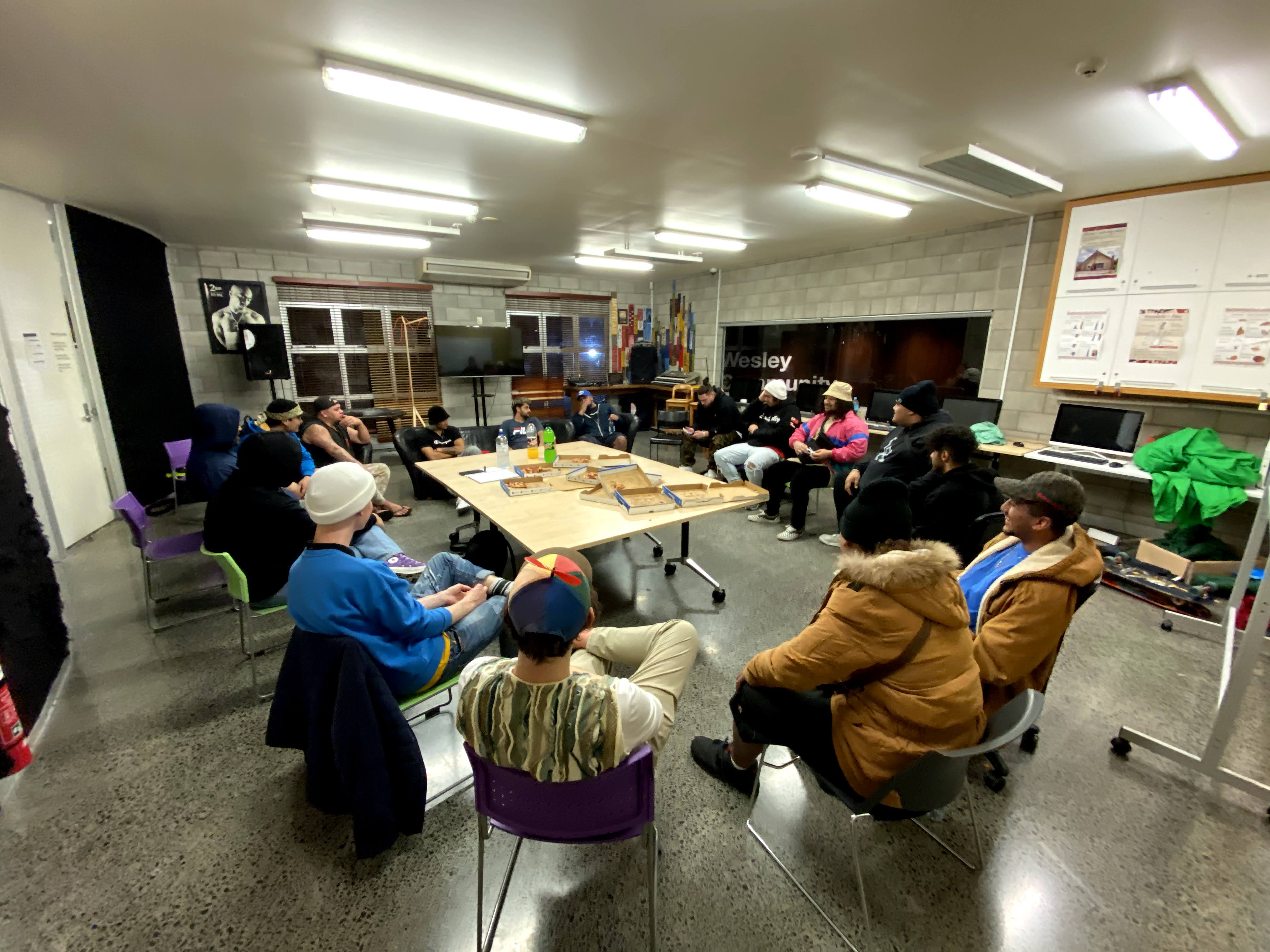 Young people gathered round a table with hip hop artists