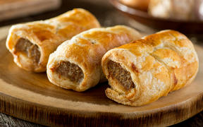 Delicious homemade sausage rolls on a wooden serving platter.