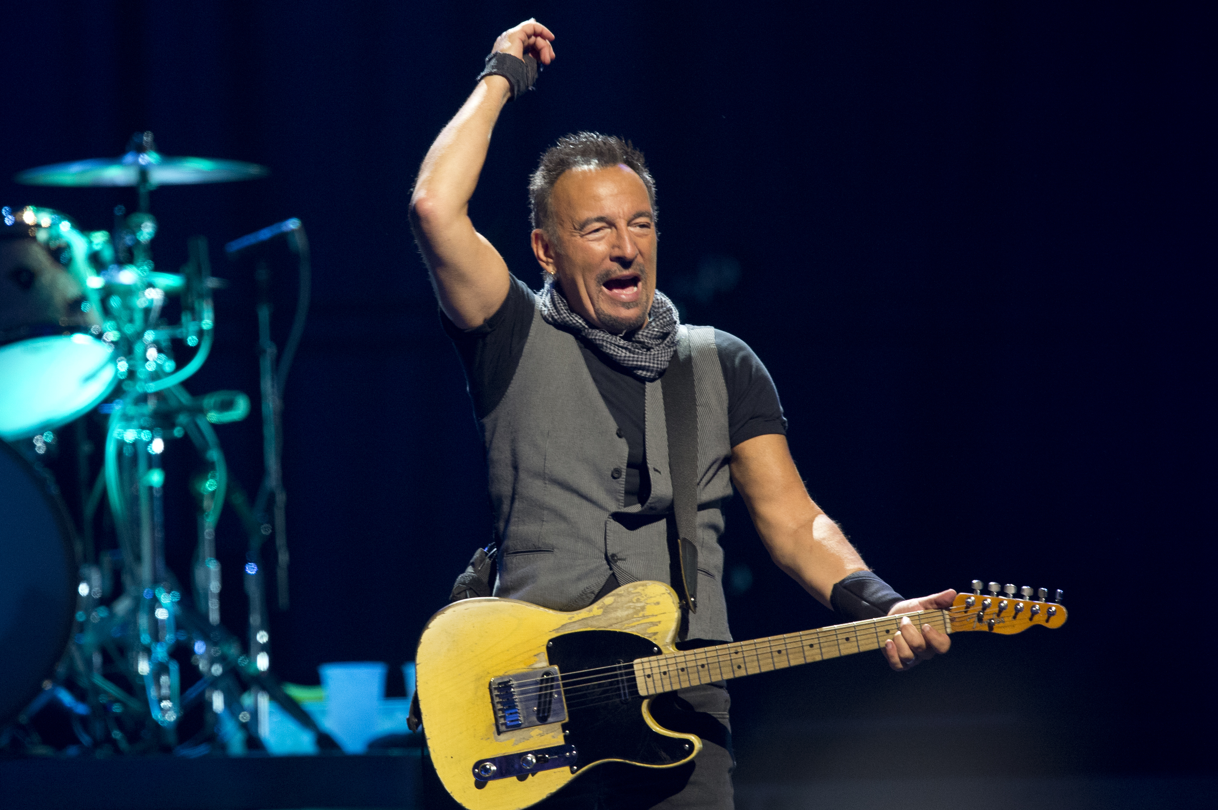 Bruce Springsteen raises his hand while playing a guitar