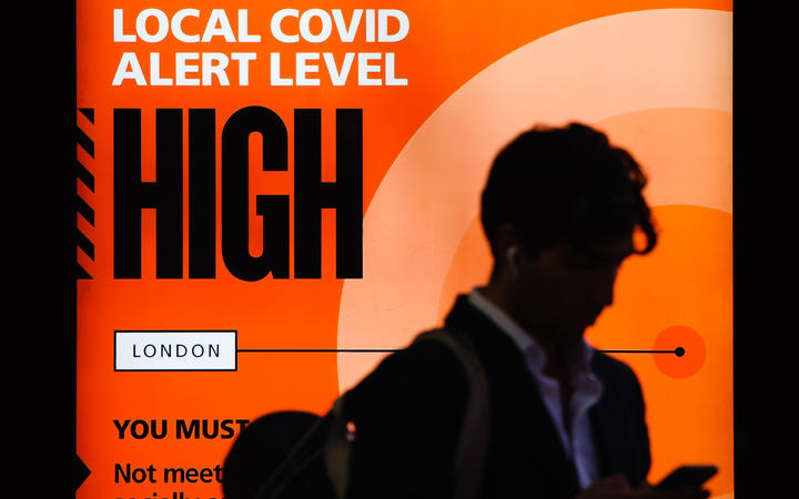 A government public information notice reminding people of 'High' (or 'Tier 2') coronavirus restrictions lights up the advertising panel of a bus stop on Knightsbridge in London, England/