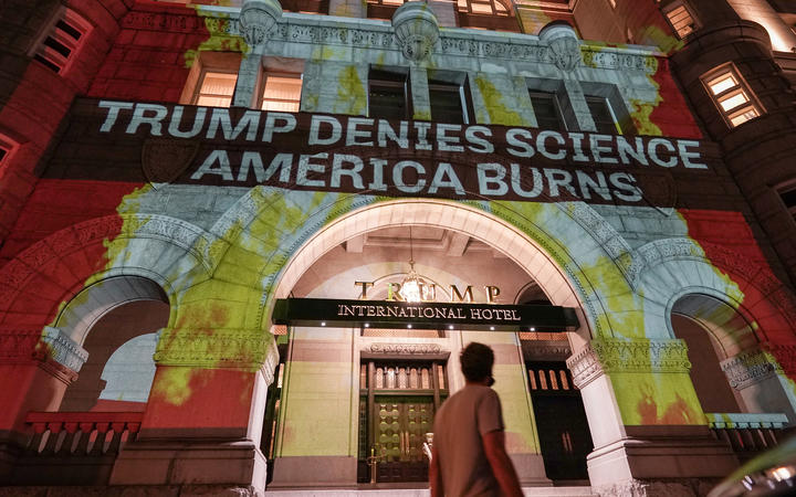 Activists project flames and commentary on the side of the Trump International Hotel in protest of President Donald Trump's response to science and climate change.