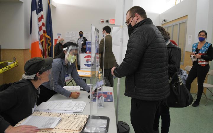 A man wearing a face mask registers for the voting at a pooling station during the Presidential election, in New York.