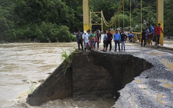 People look at the damage caused by heavy rains brought by Hurricane Eta, now degraded to a tropical storm, on a bridge over the overflooded Cahaboncito river in Panzos, Alta Verapaz, 220 km north of Guatemala City on November 6, 2020. 