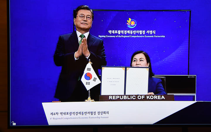 South Korea's President Moon Jae-in claps as Minister for Trade Yoo Myung-hee (right) holds up the signed RCEP agreement at the ASEAN summit held online in Hanoi on November 15, 2020.