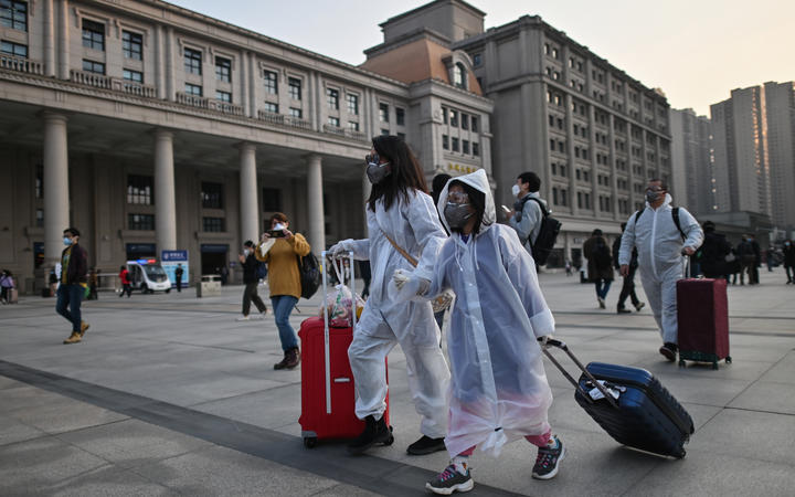 People wearing protective clothing and masks arrive at Hankou Railway Station to board one of the first trains to leave Wuhan after an outbound travel ban was lifted on April 8, 2020.