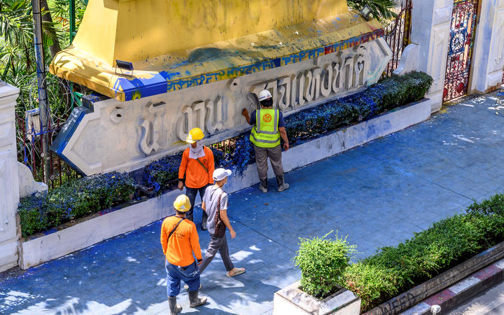 Workers inspect the damage of the paint-splashed wall of the Royal Thai Police Headquarters.