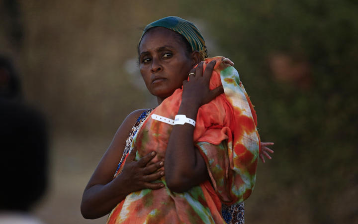 An Ethiopian refugee who fled fighting in Tigray province carries her baby as she walks at the Um Rakuba camp in Sudan's eastern Gedaref province, on November 21, 2020. 