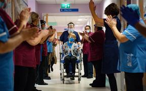 Margaret Keenan (C), 90, is applauded by staff as she returns to her ward after becoming the first person to receive the Pfizer-BioNtech Covid-19 vaccine at University Hospital in Coventry, central England, on December 8, 2020.