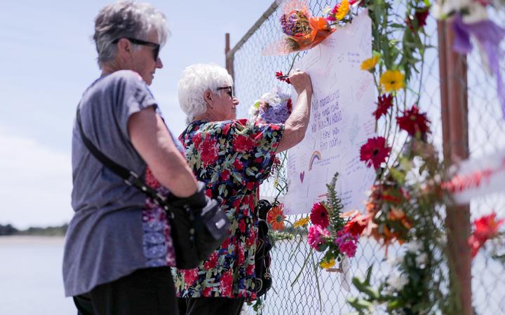 A woman writing a message on the cordon fence that's serving as a makeshift memorial.