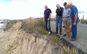 Residents survey the erosion that has partially closed the coastal route.