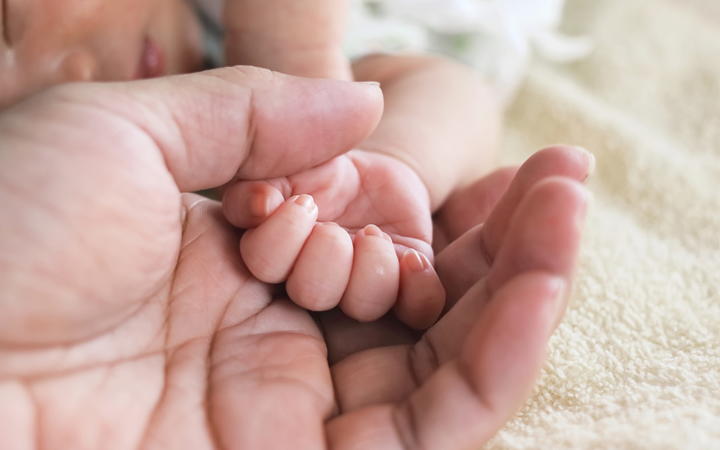 Soft focus of newborn tiny baby hand on parent hands.