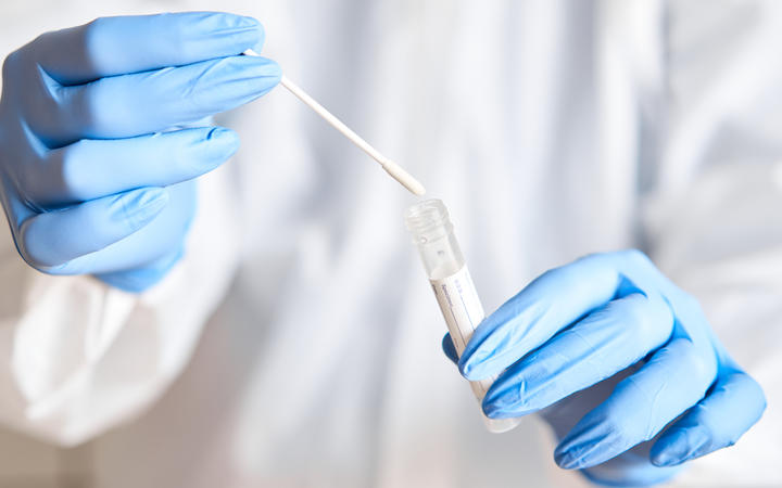 Doctor holding swab test tube for 2019-nCoV analyzing. Coronavirus test. Blue medical gloves and protective face mask for protection against covid-19 virus. Coronavirus and pandemic