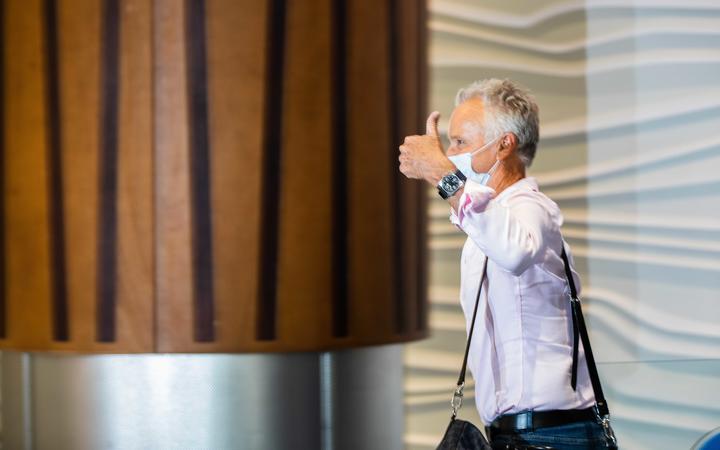 A passenger gives a thumbs-up as he walks into the arrivals hall after flying from Sydney to Auckland Airport.