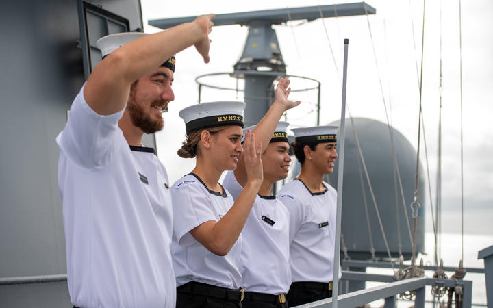 Crew onboard the HMNZS Aotearoa wave to onlookers.