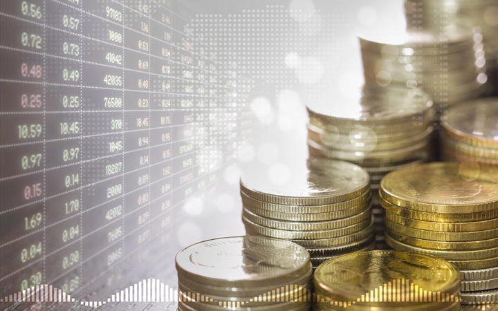 Stacks of coins money and faded stock trading board in golden light and soft bokeh with digital world map on background