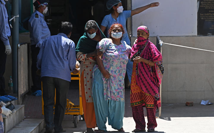 A Covid-19 coronavirus patient is helped by her relatives as she leaves a hospital in New Delhi on April 24.