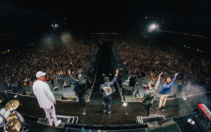 Six60 waving to fans from the stage at Eden Park.