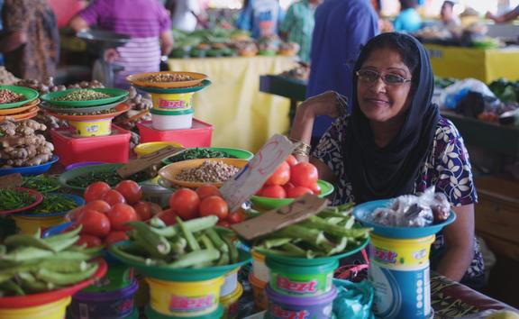 A Fijian Indian woman sits at her vibrant food stall at Suva Market
