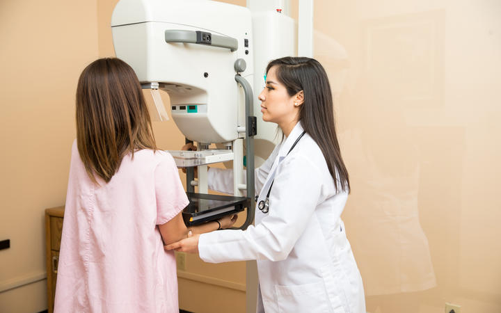 Doctor setting a patient in the correct position to get a mammogram. Breast cancer screening.