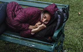 File image: A homeless woman sleeps on a bench 