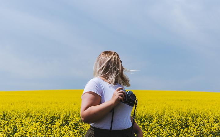 blonde woman with camera in field