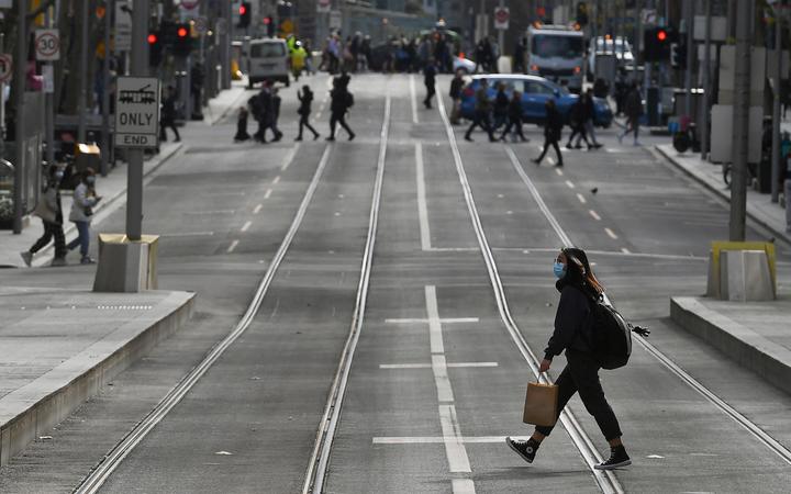 A shopper crosses the street in the central business district in Melbourne on July 7, 2021 