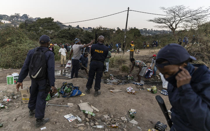 Des policiers se disputent avec des membres de la communauté à côté d'un entrepôt pillé stockant de l'alcool à Durban le 16 juillet 2021, 