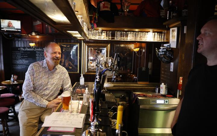 A customer drinks a pint standing at the bar of a pub in central London on July 19, 2021 as coronavirus restrictions are lifted. 