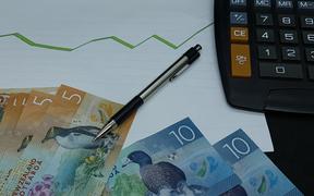 New Zealand banknotes, pen and calculator on background with rising trend green line