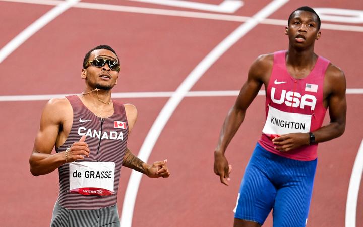 Gold medal winner Andre de Grasse of Canada alongside Erriyon Knighton of the United States cross the finish line in the men's 200m final during the athletics event at the Tokyo 2020 Olympic Games.