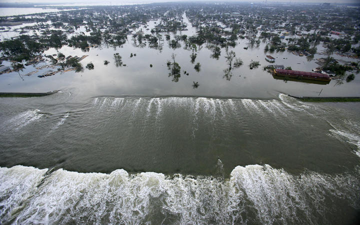 Water spills over a levee along the Inner Harbor Navigational Canal in the aftermath of Hurricane Katrina 30 August, 2005 in New Orleans.