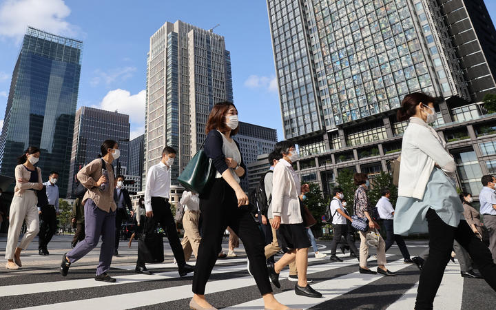 People wearing face masks are seen during commuting hour under a refreshing clear blue sky in front of Tokyo Station in Chiyoda Ward, Tokyo.