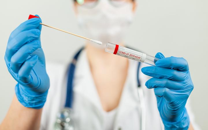 Test for coronavirus Covid-19. Female doctor or nurse doing lab analysis of a nasal swab in a hospital laboratory. Medical technologist holding a COVID-19 smear kit, wearing protective gloves from