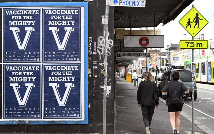 People walk past a sign encouraging people to get vaccinated in Melbourne on August 31, 2021 as the city experiences it's sixth lockdown as it battles an outbreak of the Delta variant of coronavirus. 