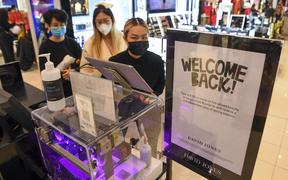 People shop in a department store in Melbourne on October 29, 2021 as the city further lifts Covid restrictions allowing non-essential retail shops to open and travel to the regions of Victoria after the city's sixth lockdown. 